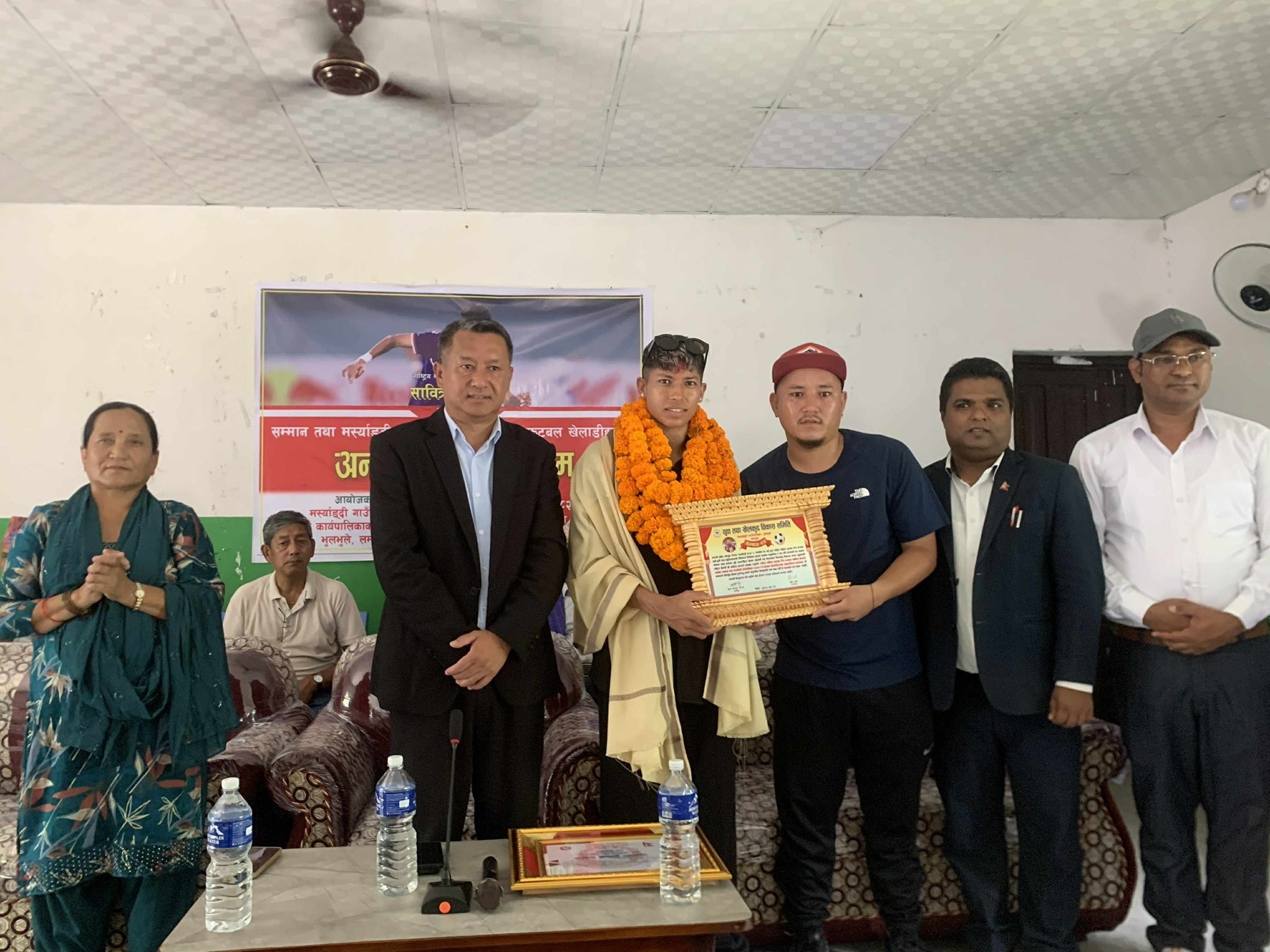 नेपाली राष्ट्रिय महिला फुटबल टोलीकी कप्तान सावित्रा भण्डारी ‘साम्बा’ लाई सम्मानपत्र प्रदान गर्दै लमजुङको मर्स्याङ्दी गाउँपालिका अध्यक्ष अर्जुन गुरुङ । तस्बिरः अनुज अधिकारी